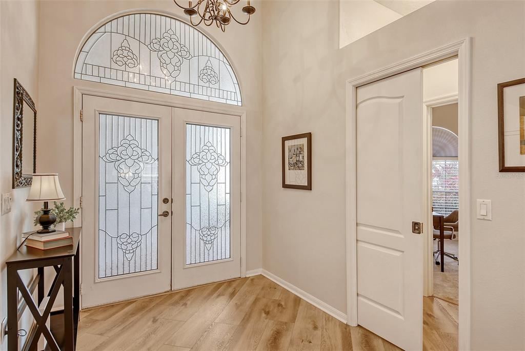 An entryway features double front doors with decorative glass, light wood flooring, and a chandelier — 6738 PLEASANT HILL ROAD, BRADENTON, FL