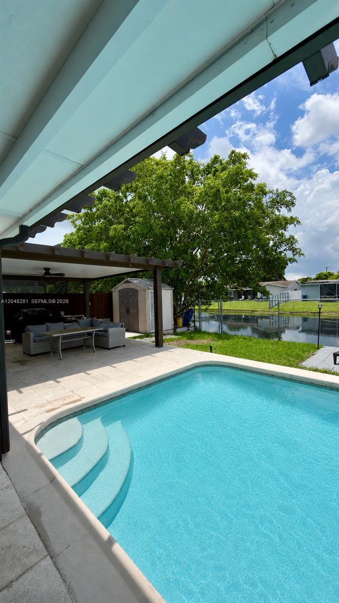 A swimming pool sits on a patio next to a covered seating area and canal — 9170 NW 24th Pl, Sunrise FL 33322, SUNRISE, FL