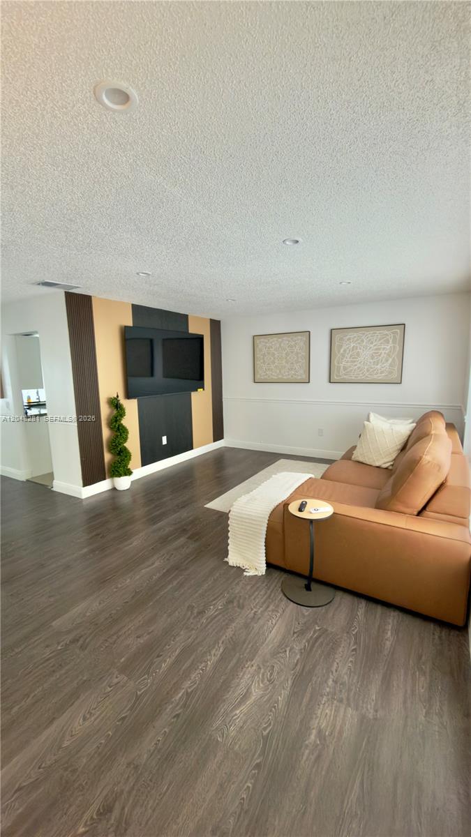 A living room features dark wood flooring, a tan sectional sofa, and a wood-paneled accent wall — 9170 NW 24th Pl, Sunrise FL 33322, SUNRISE, FL