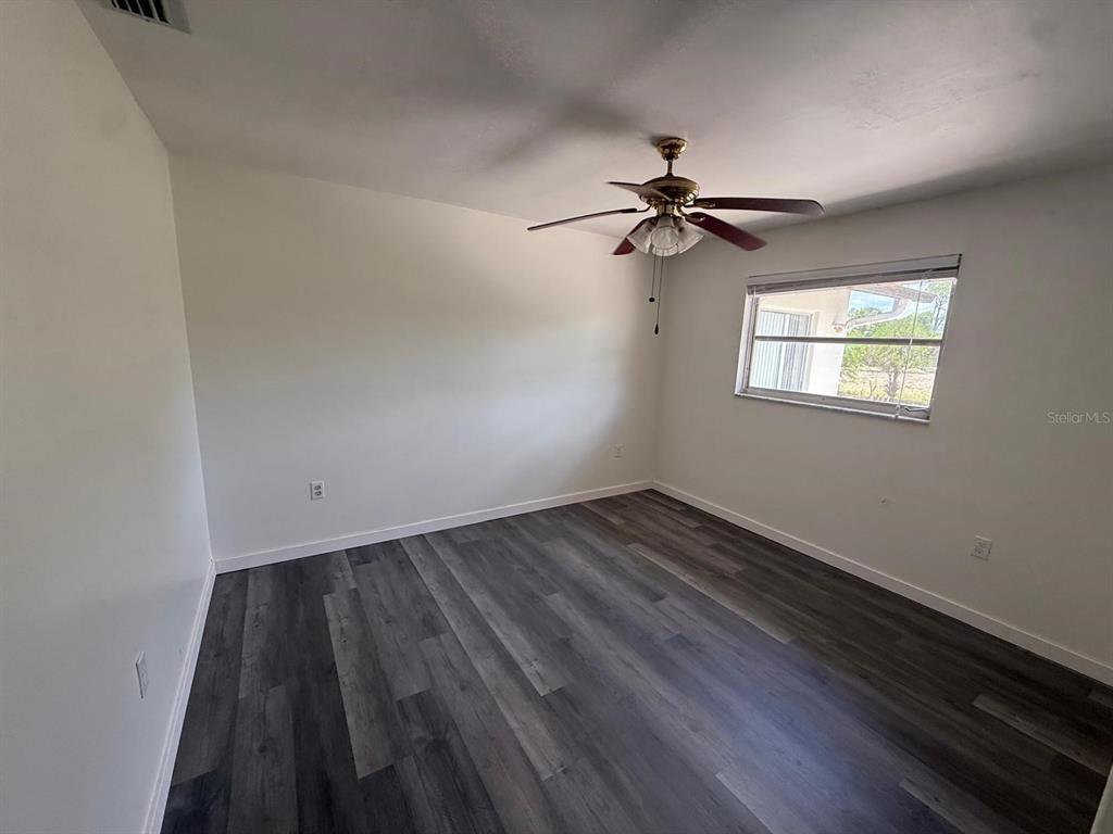 An empty bedroom features white walls, a ceiling fan, and dark wood-look laminate flooring — 239 ANNAPOLIS LANE, ROTONDA WEST, FL