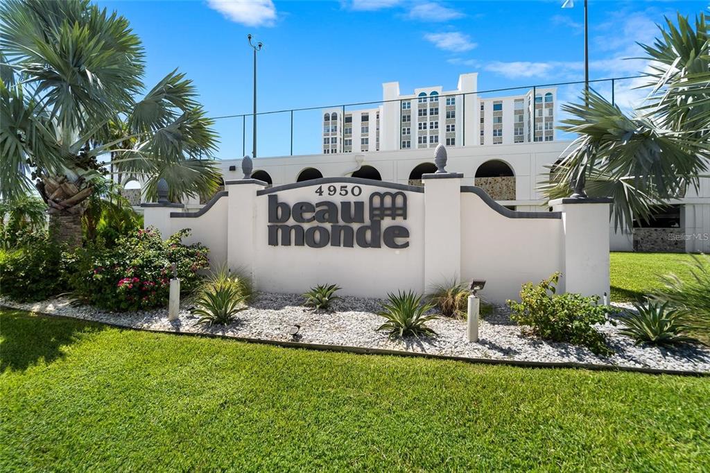 A white monument sign for Beau Monde stands in front of a multi-story residential building — 4950 GULF BOULEVARD UNIT 807, ST PETE BEACH, FL