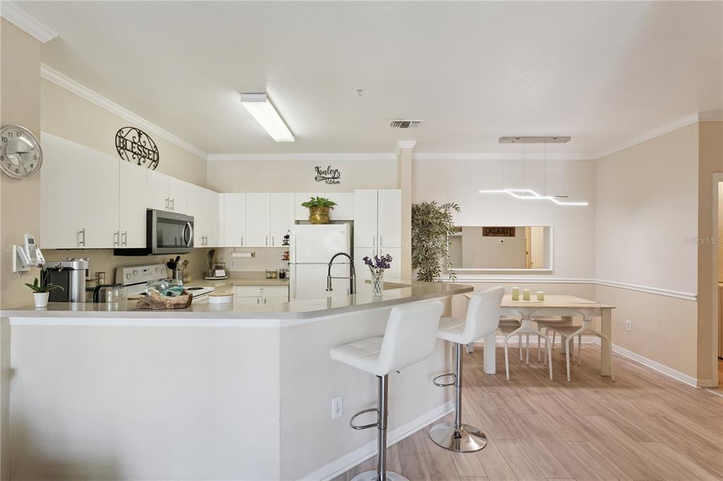 A kitchen with white cabinets and a breakfast bar opens into a dining area — 3751 CONROY ROAD UNIT 2325, ORLANDO, FL