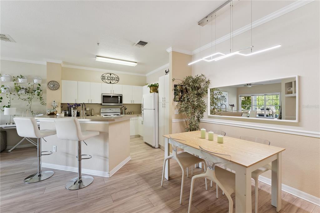 A kitchen with white cabinets and a breakfast bar adjacent to a dining area — 3751 CONROY ROAD UNIT 2325, ORLANDO, FL
