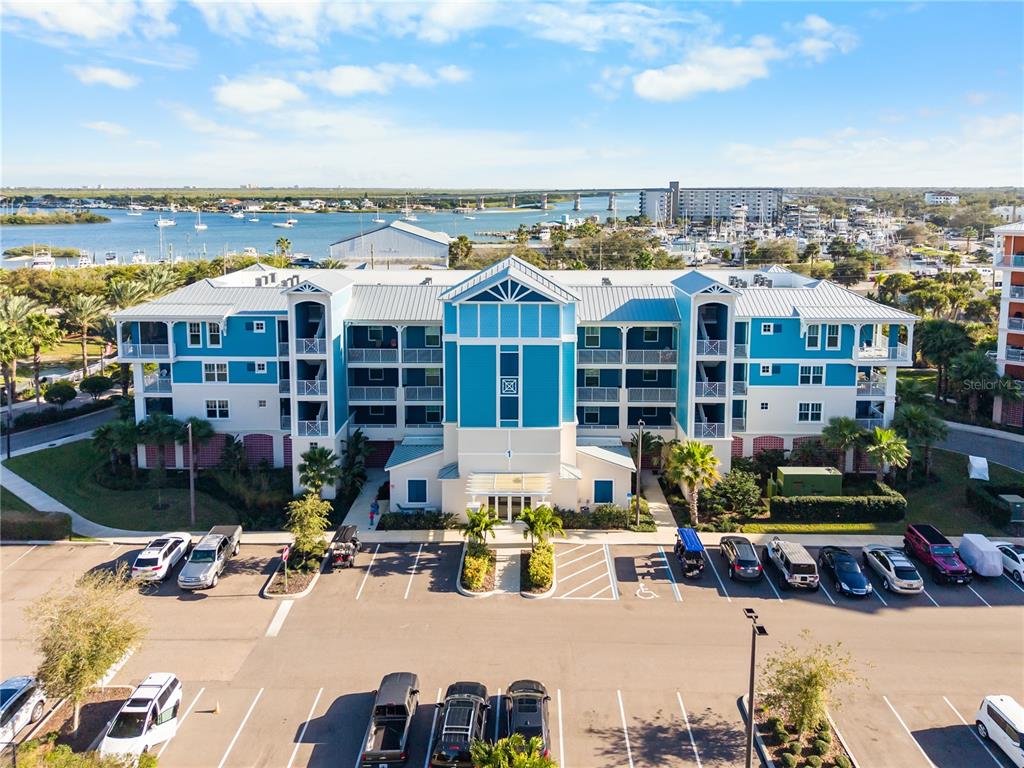 An aerial view shows a blue multi-story apartment building with a parking lot in front — 1 RIVERWALK DRIVE UNIT 306, NEW SMYRNA BEACH, FL