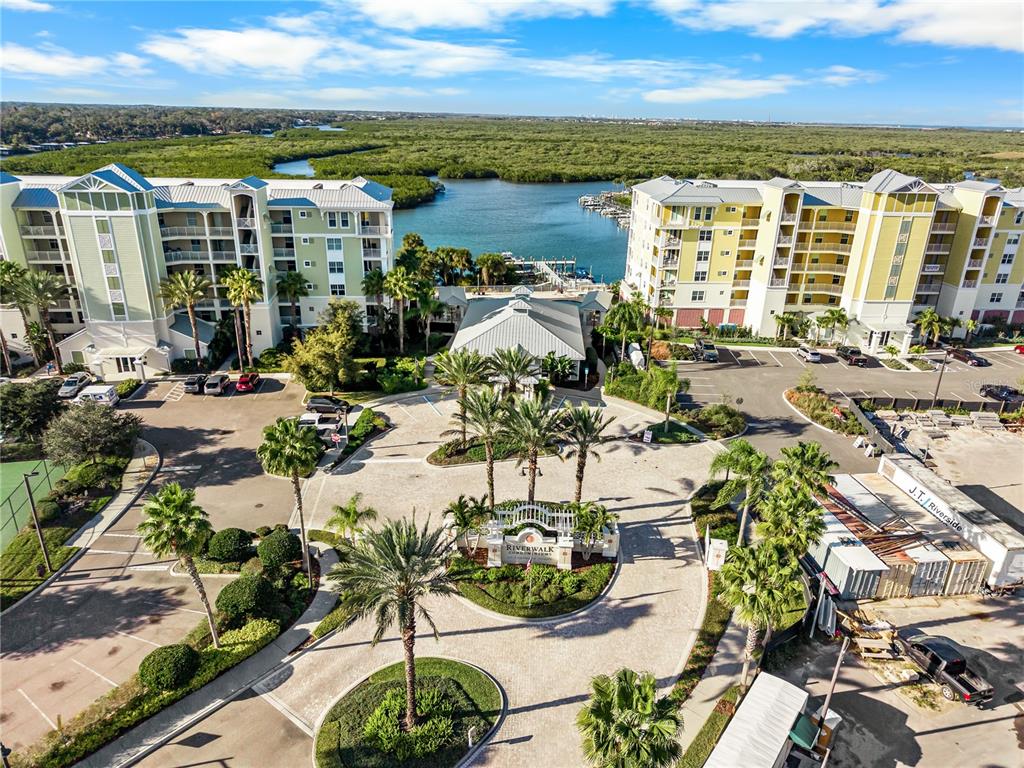 An aerial view shows two large apartment buildings flanking a central courtyard with palm trees — 1 RIVERWALK DRIVE UNIT 306, NEW SMYRNA BEACH, FL