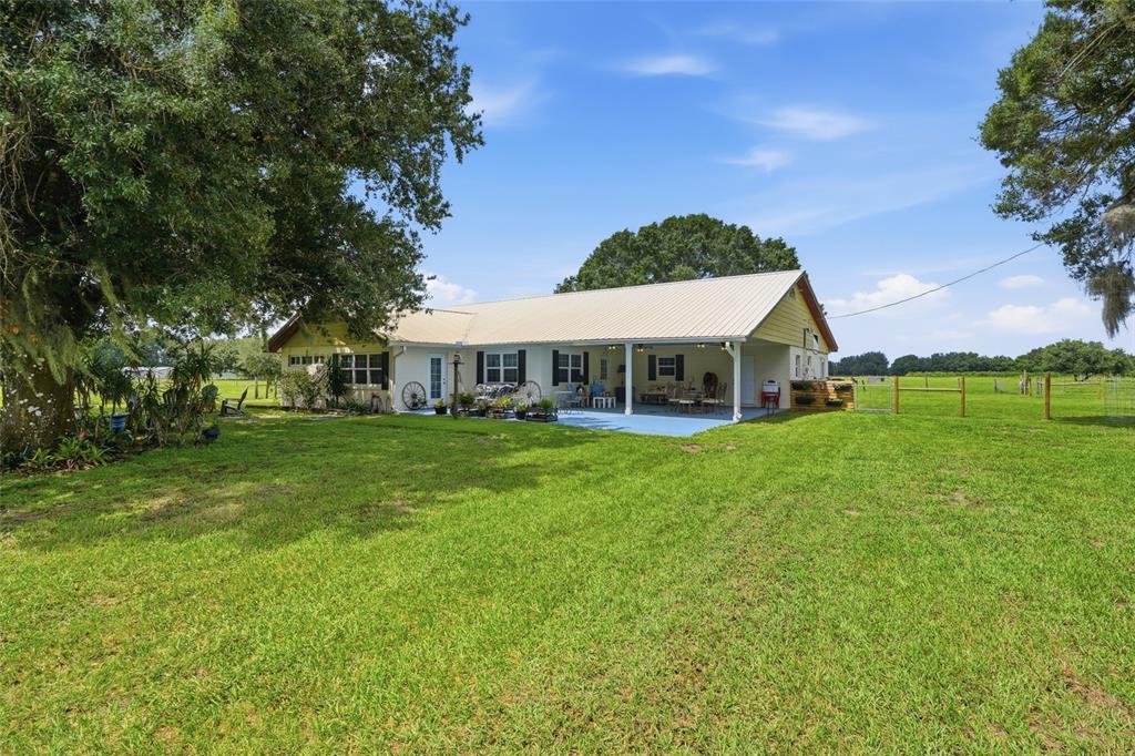 A one-story house with a metal roof and a large covered patio sits on grass — 6902 JOHNSTON ROAD, ZOLFO SPRINGS, FL