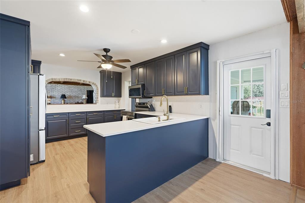 A kitchen features dark blue cabinets, white countertops, and a white exterior door — 6902 JOHNSTON ROAD, ZOLFO SPRINGS, FL