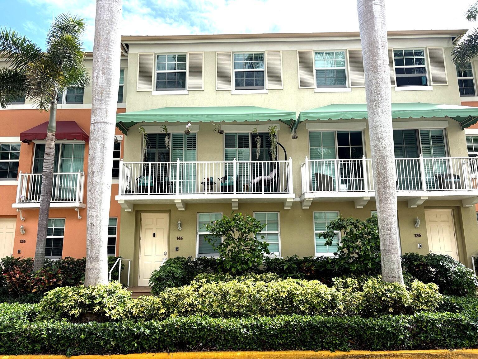 The exterior of a multi-story townhouse building features balconies, green awnings, and palm trees — 146 Moorings Drive, Lantana FL 33462, LANTANA, FL