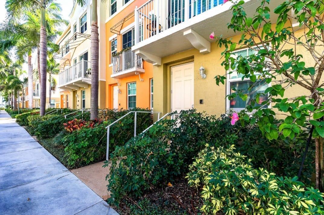 A row of colorful townhouses with balconies and lush landscaping along a concrete sidewalk — 146 Moorings Drive, Lantana FL 33462, LANTANA, FL