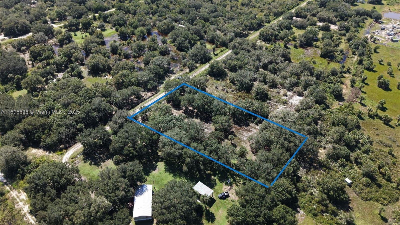 An aerial view shows a rectangular plot of land outlined in blue amidst wooded terrain — 20125 NW 300TH ST, Okeechobee FL 34972, OKEECHOBEE, FL