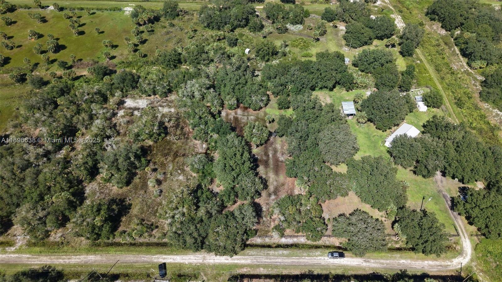 An aerial view shows a rural property with dense trees, open grassy areas, and structures — 20125 NW 300TH ST, Okeechobee FL 34972, OKEECHOBEE, FL