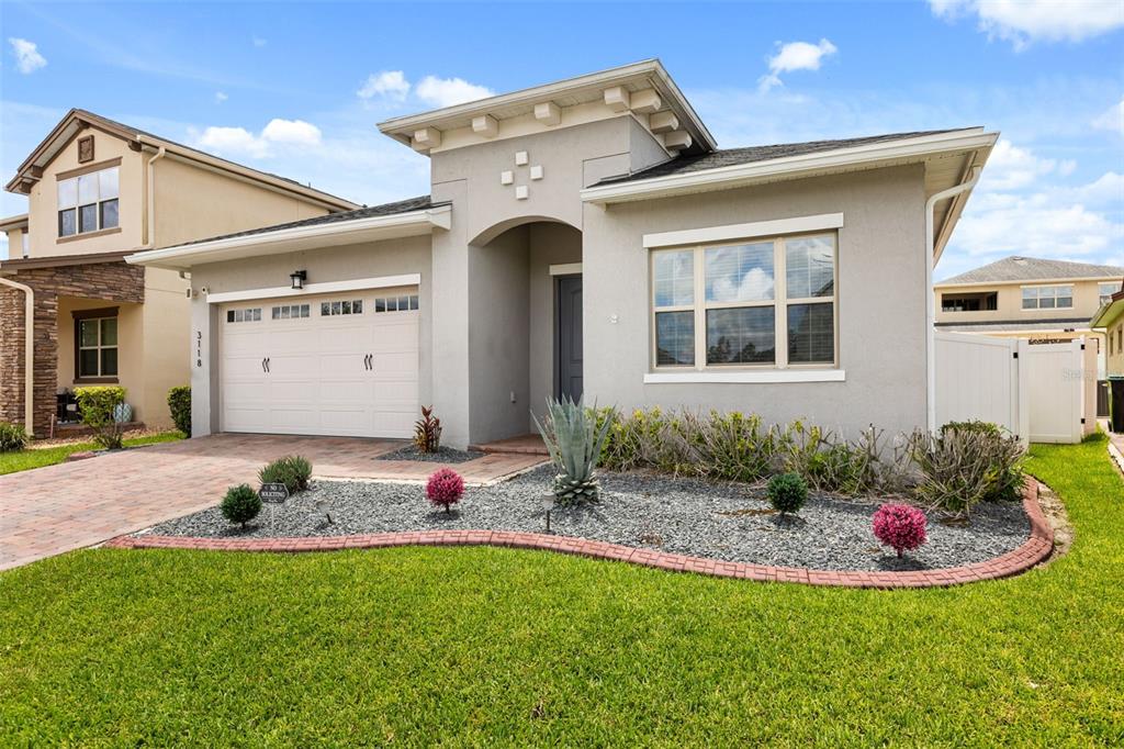 A single-story house with a beige stucco exterior, a two-car garage, and landscaped front yard — 3118 RESIDENCE EAST WAY, ORLANDO, FL