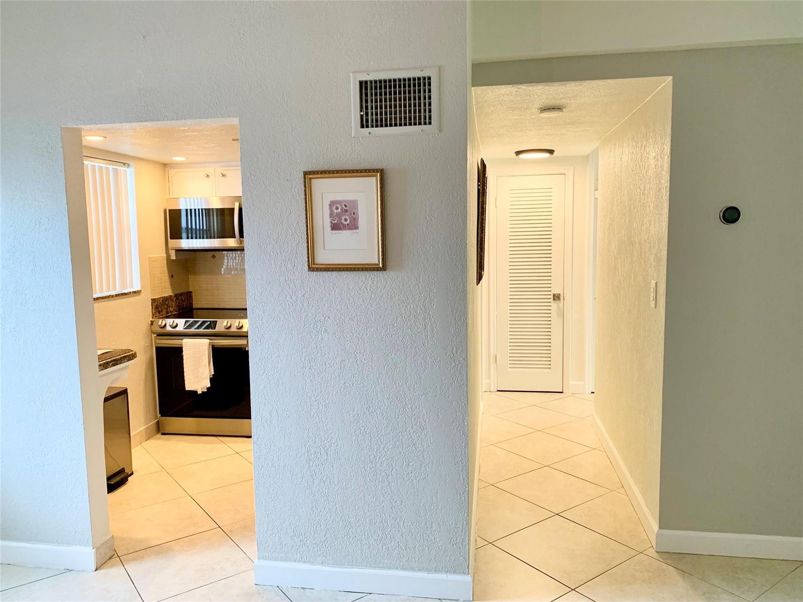 A view of a kitchen entrance and a hallway with tiled floors and white walls — 6550 Winfield Boulevard # 105, Margate FL 33063, MARGATE, FL