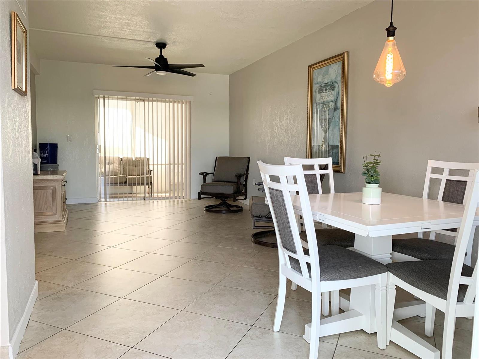 A dining area with a white table and chairs sits beside a living room space — 6550 Winfield Boulevard # 105, Margate FL 33063, MARGATE, FL