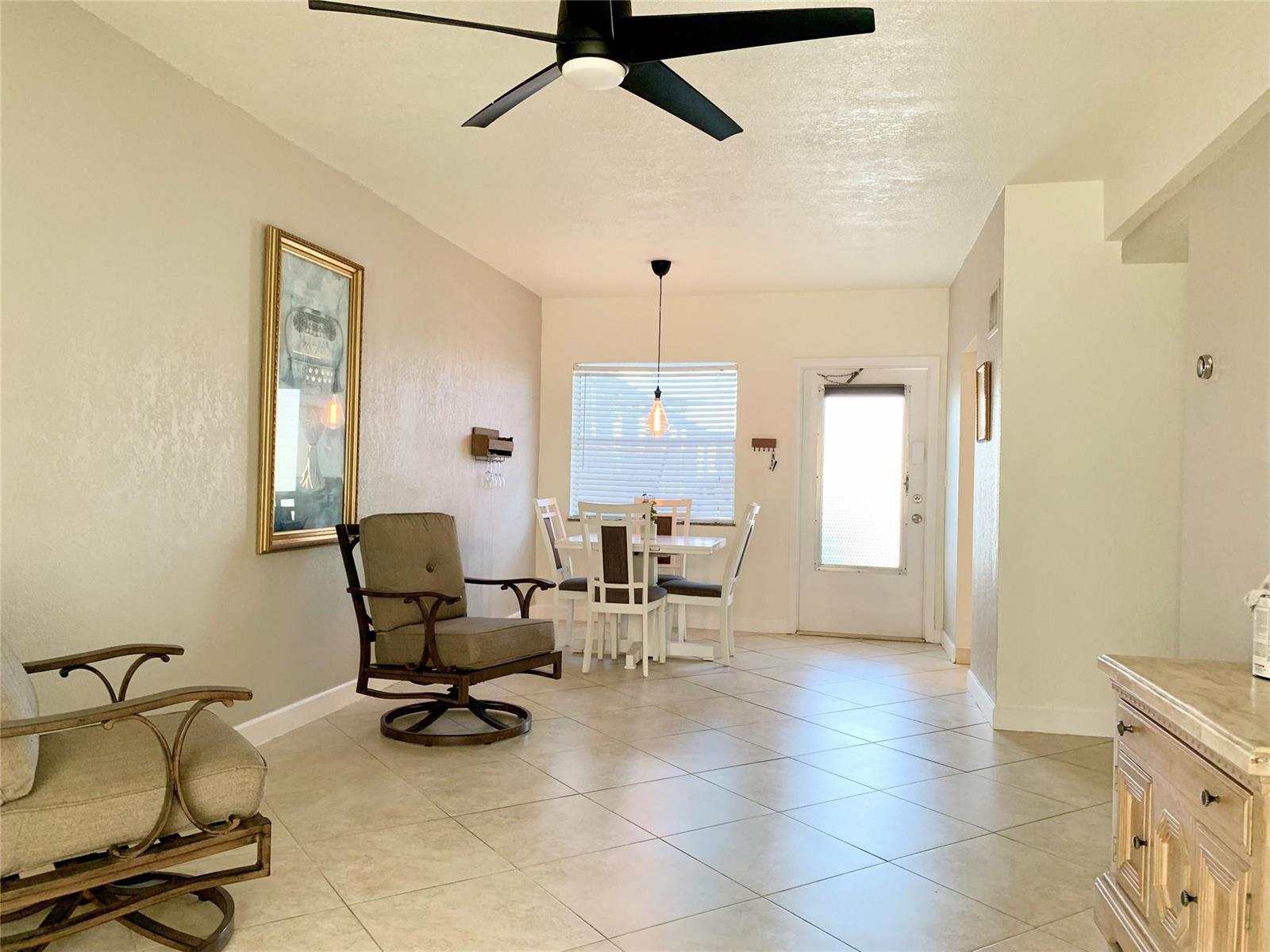A dining area with a white table and chairs sits near a door and tile flooring — 6550 Winfield Boulevard # 105, Margate FL 33063, MARGATE, FL