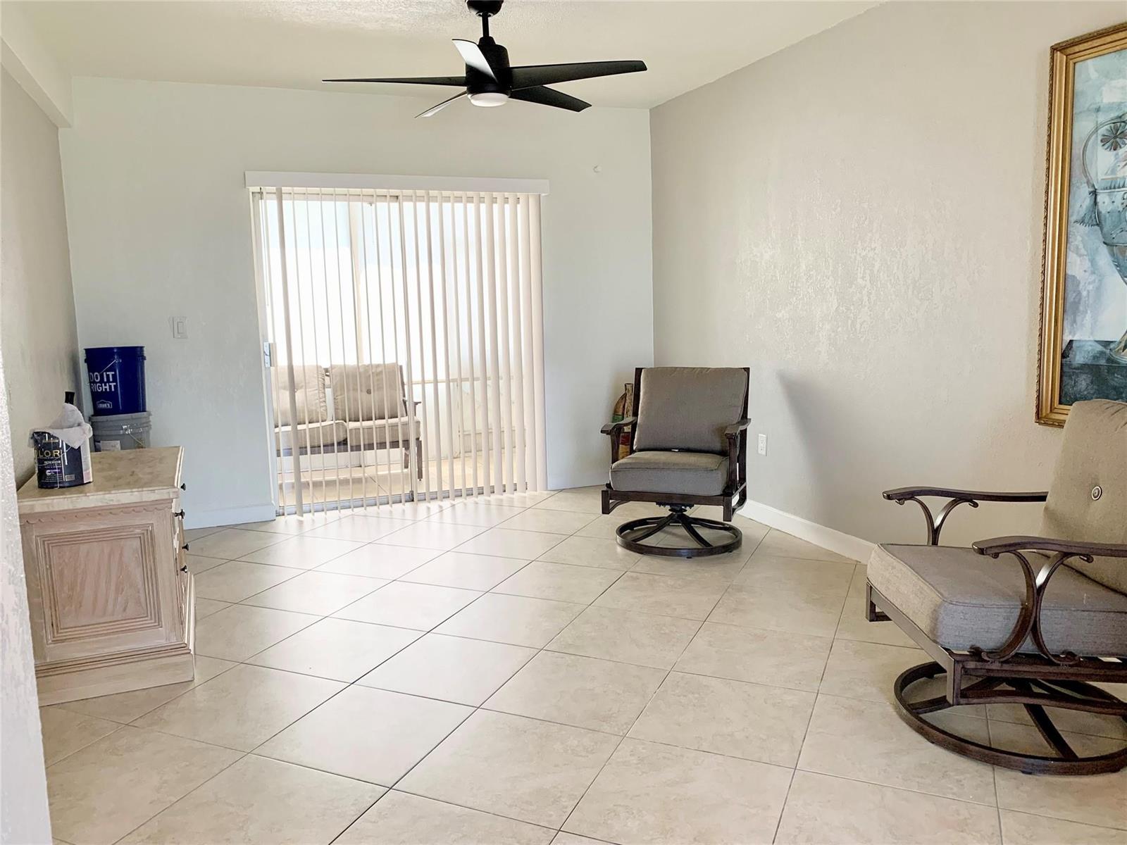 A room with tile floors, a ceiling fan, two swivel chairs, and a sliding glass door — 6550 Winfield Boulevard # 105, Margate FL 33063, MARGATE, FL