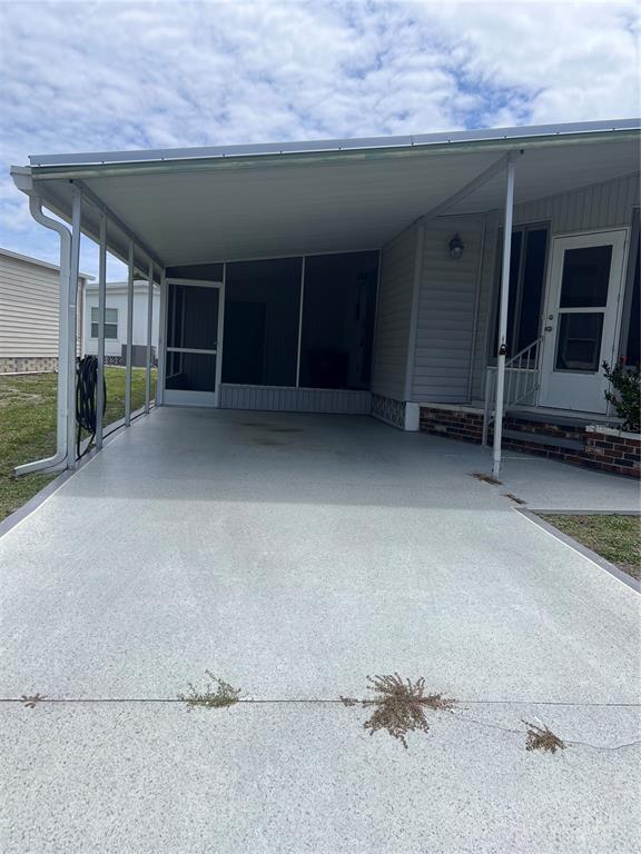 A concrete carport leads to a screened-in porch and the entrance of a mobile home — 103 S FIJI CIRCLE, ENGLEWOOD, FL