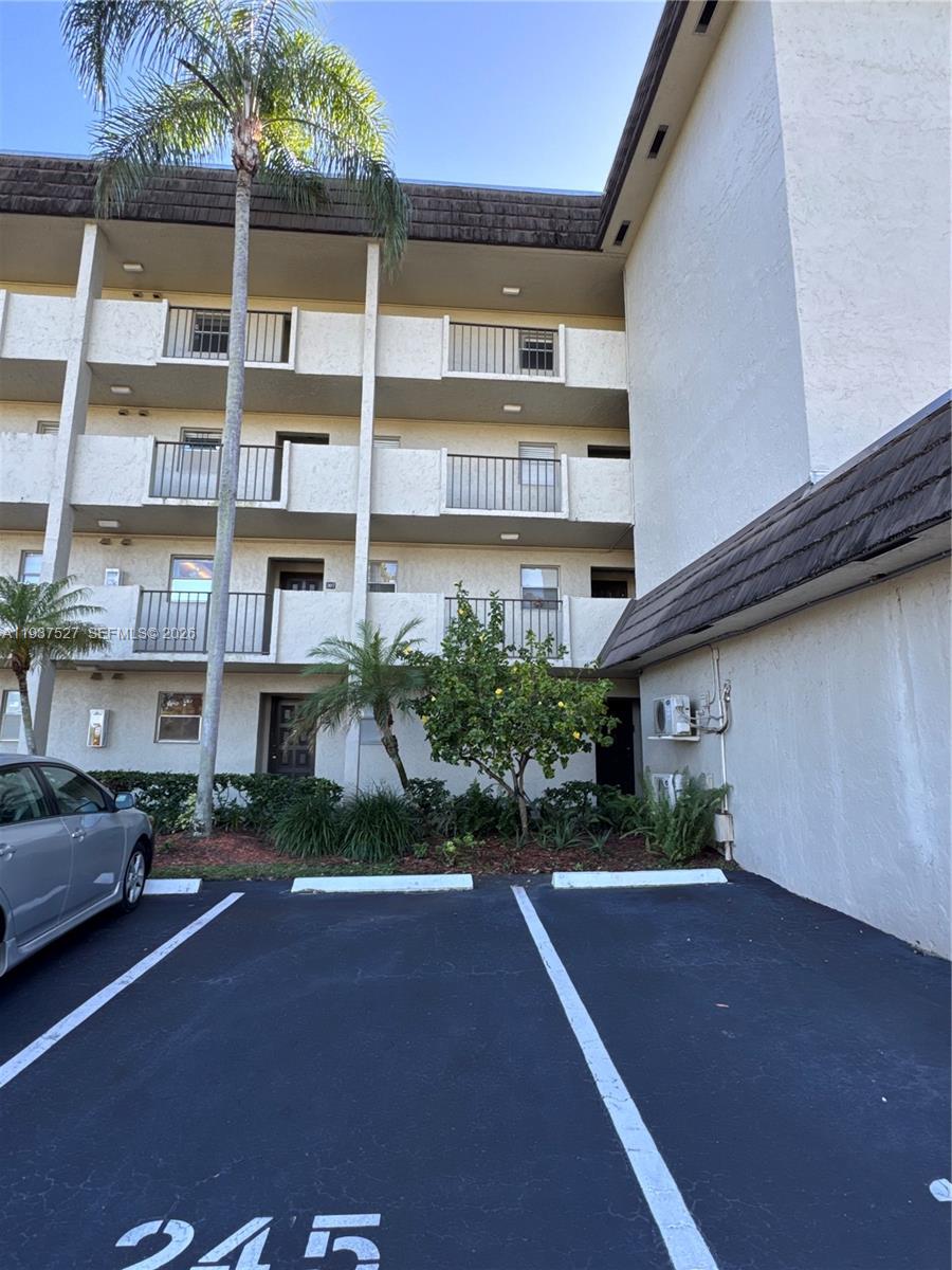 A multi-story apartment building exterior features balconies, a palm tree, and marked parking spaces — 6080 NW 44th St # 107, Lauderhill FL 33319, LAUDERHILL, FL