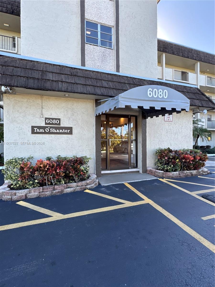 The exterior of a multi-story apartment building features a covered entrance with a gray awning — 6080 NW 44th St # 107, Lauderhill FL 33319, LAUDERHILL, FL