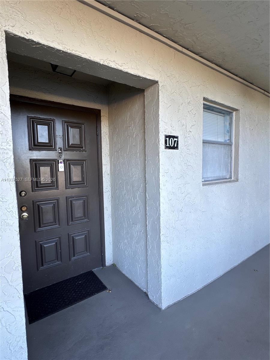 A brown front door with a black mat and the number 107 on the wall — 6080 NW 44th St # 107, Lauderhill FL 33319, LAUDERHILL, FL