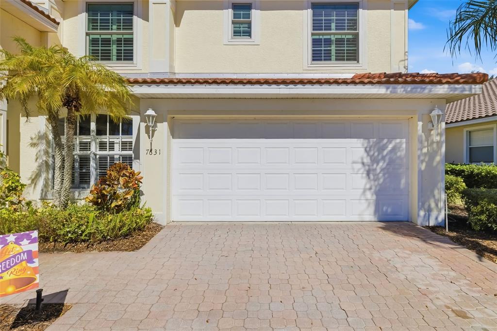 A two-story house features a white two-car garage and a paved driveway — 7631 DESERT INN WAY, LAKEWOOD RANCH, FL