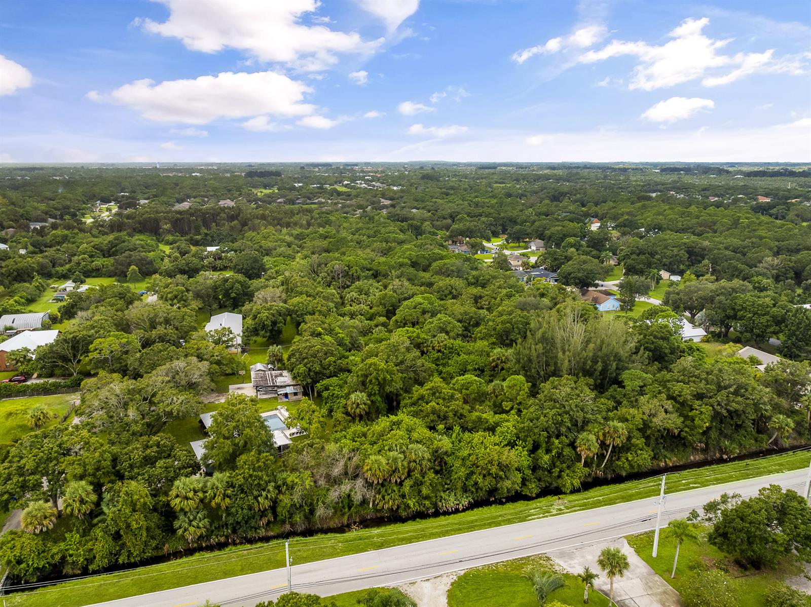 An aerial view shows a residential property with a pool surrounded by dense forest — 6145 45th Street, Vero Beach FL 32967, VERO BEACH, FL