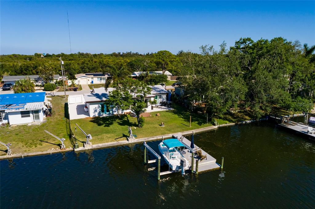 An aerial view shows a waterfront house with a private dock and a boat — 9298 SUN ISLE DRIVE NE, ST PETERSBURG, FL