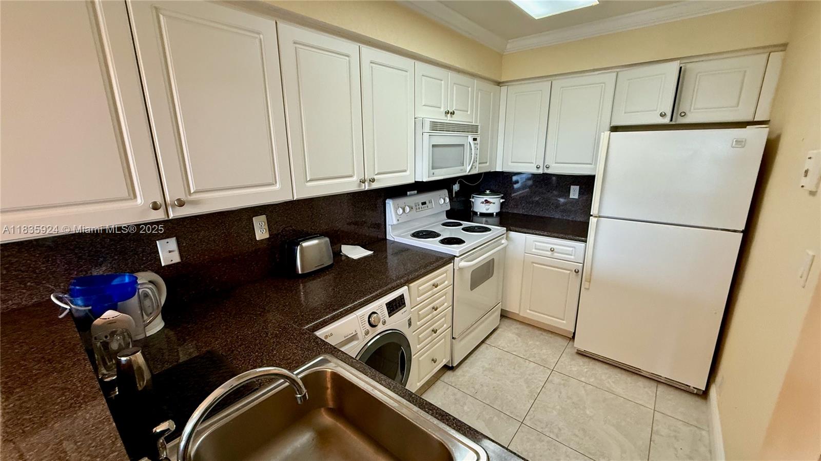 A kitchen features white cabinets, dark granite countertops, a white stove, and a built-in washer — 2501 S Ocean Dr # 427, Hollywood FL 33019, HOLLYWOOD, FL