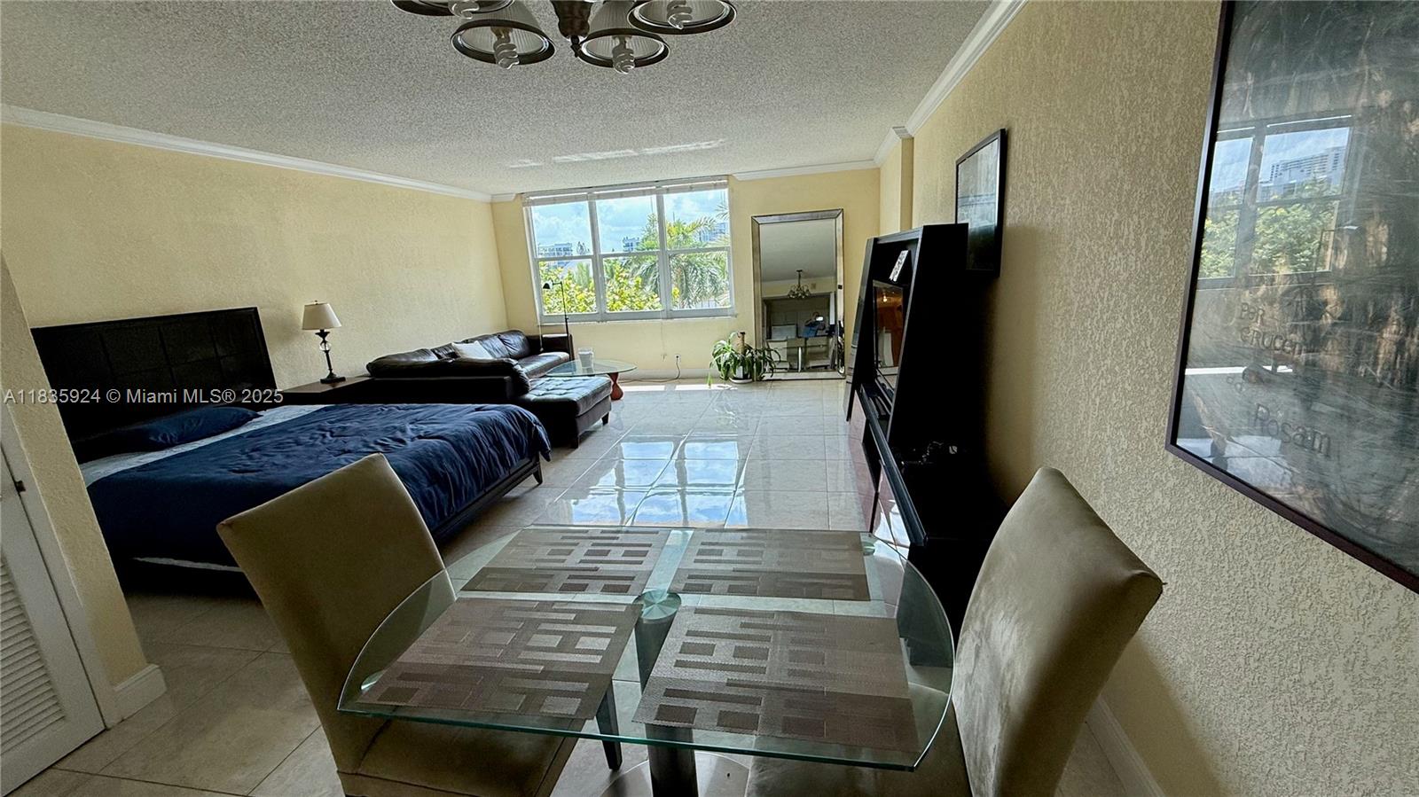 A studio apartment features a bed, a living area, and a glass dining table — 2501 S Ocean Dr # 427, Hollywood FL 33019, HOLLYWOOD, FL