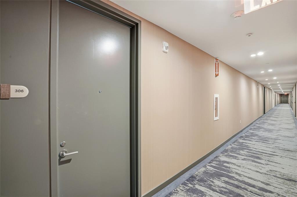 A gray apartment door labeled 306 opens into a long, carpeted residential hallway — 400 CENTRAL AVENUE UNIT 306, ST PETERSBURG, FL