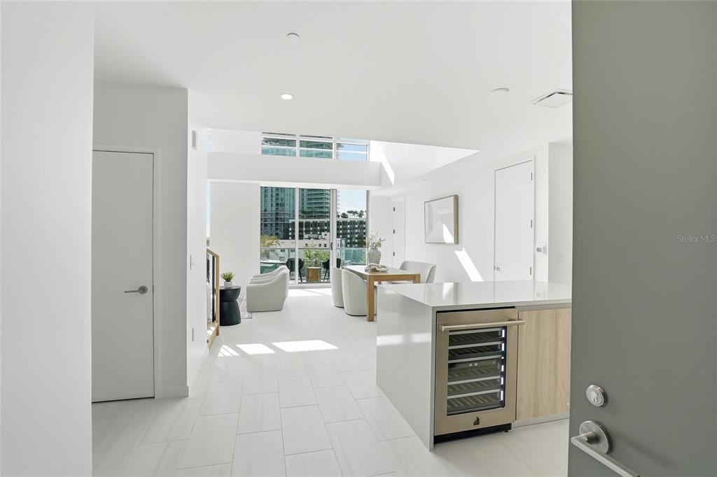 A modern, white-toned open-concept living and dining area features a kitchen island with a wine cooler — 400 CENTRAL AVENUE UNIT 306, ST PETERSBURG, FL