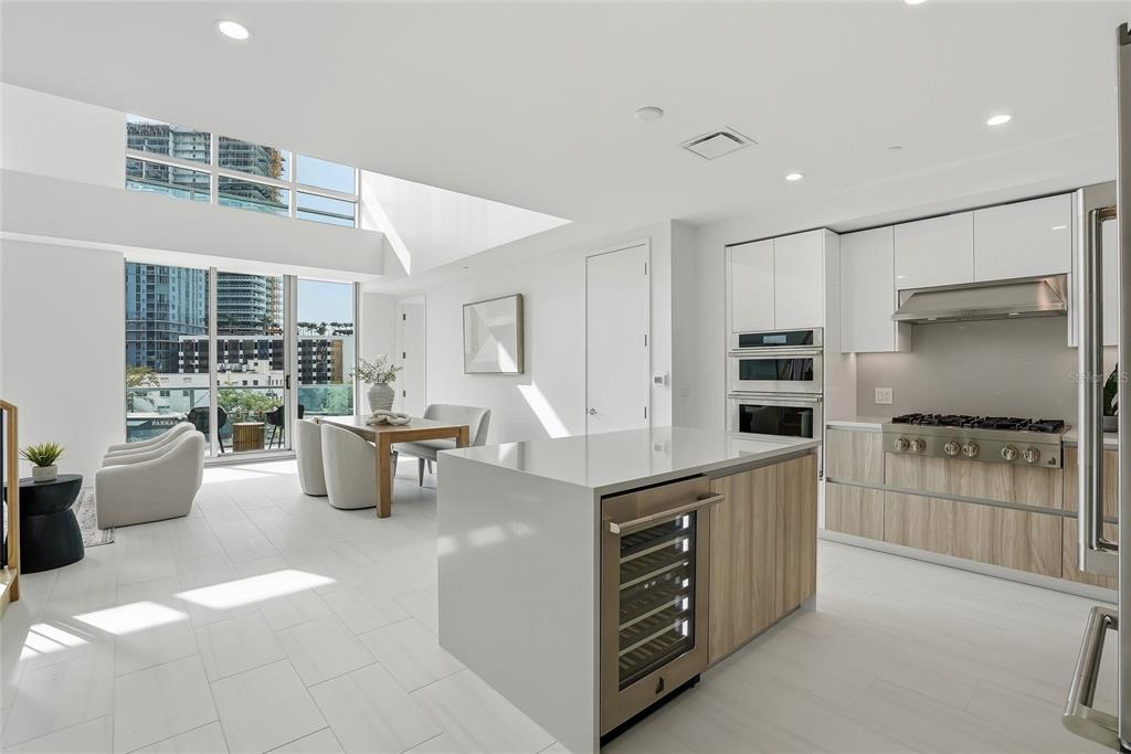 A modern kitchen and dining area with white cabinetry, wood accents, and floor-to-ceiling windows — 400 CENTRAL AVENUE UNIT 306, ST PETERSBURG, FL
