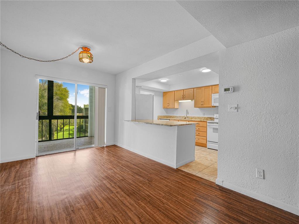 A dining area with wood-look flooring opens to a kitchen with light wood cabinets — 1130 N LAKE PARKER AVENUE UNIT A301, LAKELAND, FL