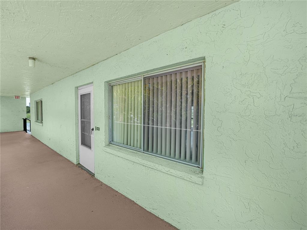An exterior walkway with a light green stucco wall, a white door, and a window — 1130 N LAKE PARKER AVENUE UNIT A301, LAKELAND, FL