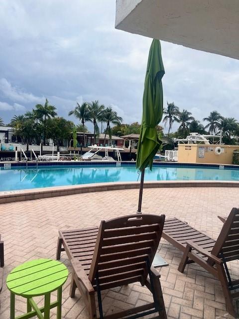 A swimming pool overlooks a canal with boats, viewed from a patio with lounge chairs — 2000 NE 135th St # 601, North Miami FL 33181, NORTH MIAMI, FL