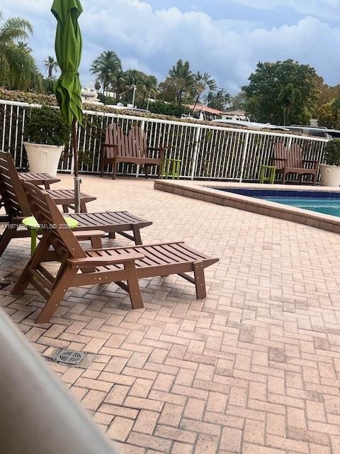 A pool deck features wooden lounge chairs, a green umbrella, and a white fence — 2000 NE 135th St # 601, North Miami FL 33181, NORTH MIAMI, FL