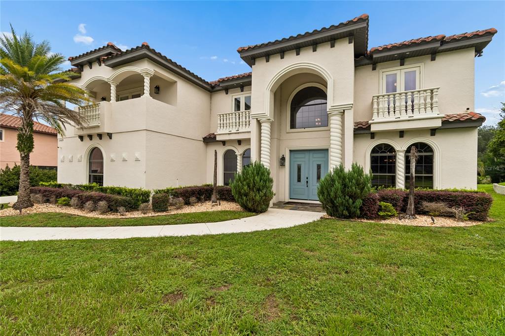 A two-story Mediterranean-style house with a light-colored stucco exterior, arched windows, and a tiled roof — 11419 CYPRESS HILL STREET, CLERMONT, FL