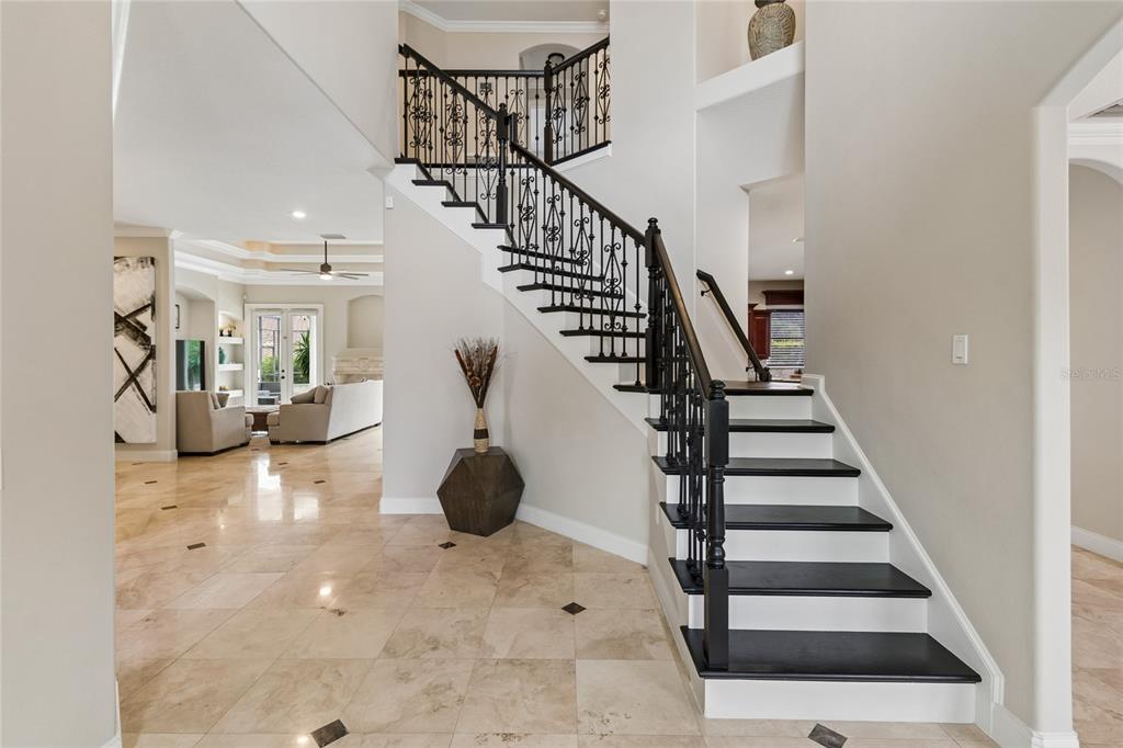 A foyer features a dark wood staircase with wrought iron railings and beige tile flooring — 11419 CYPRESS HILL STREET, CLERMONT, FL