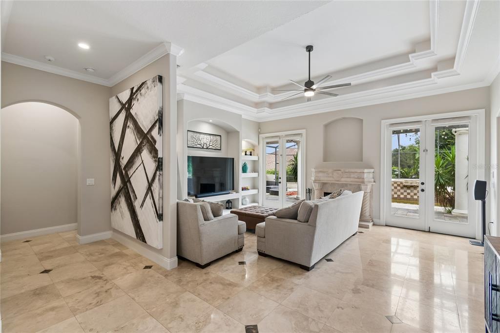 A living room features a tray ceiling, stone fireplace, tile flooring, and glass patio doors — 11419 CYPRESS HILL STREET, CLERMONT, FL