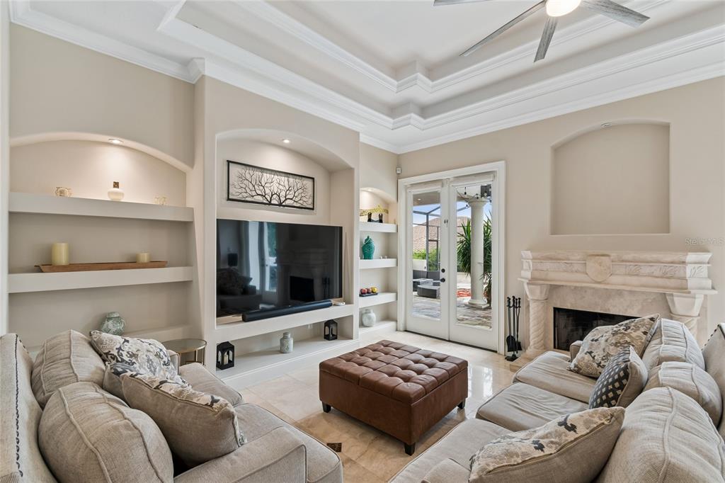 A living room features a fireplace, built-in shelving, a television, and a leather ottoman — 11419 CYPRESS HILL STREET, CLERMONT, FL