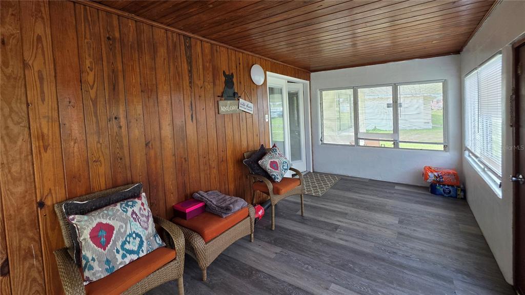 A sunroom features wood-paneled walls, a wood-plank ceiling, gray flooring, and wicker furniture — 13330 FORT KING ROAD, DADE CITY, FL