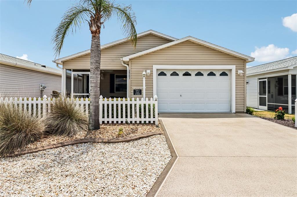 A beige single-story house features a white picket fence, a palm tree, and a garage — 2561 BIRCH AVENUE, THE VILLAGES, FL