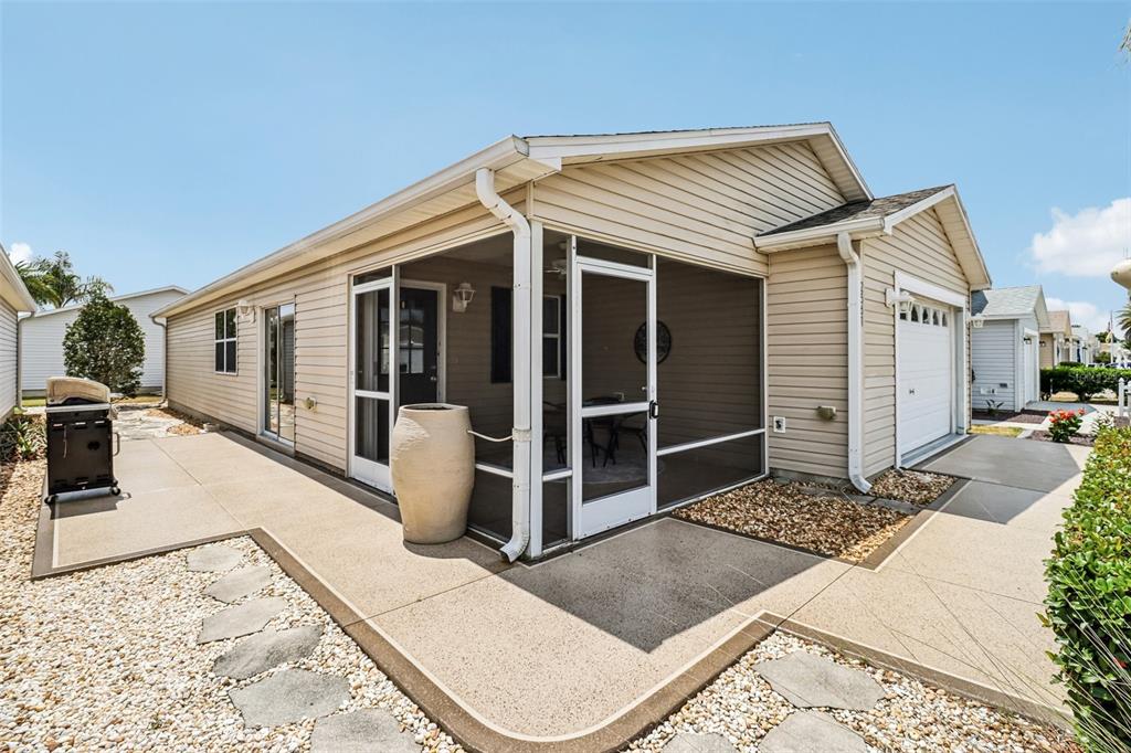 A beige house exterior features a screened-in porch, a garage, and a concrete patio — 2561 BIRCH AVENUE, THE VILLAGES, FL
