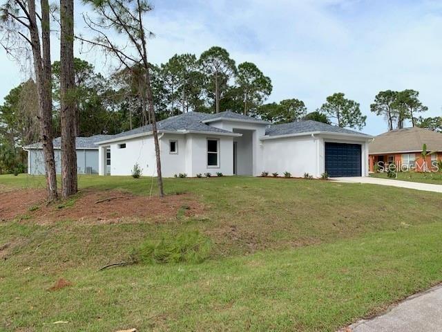 A white single-story house with a dark garage door sits on a grassy lot — 1455 HARBELL STREET, NORTH PORT, FL