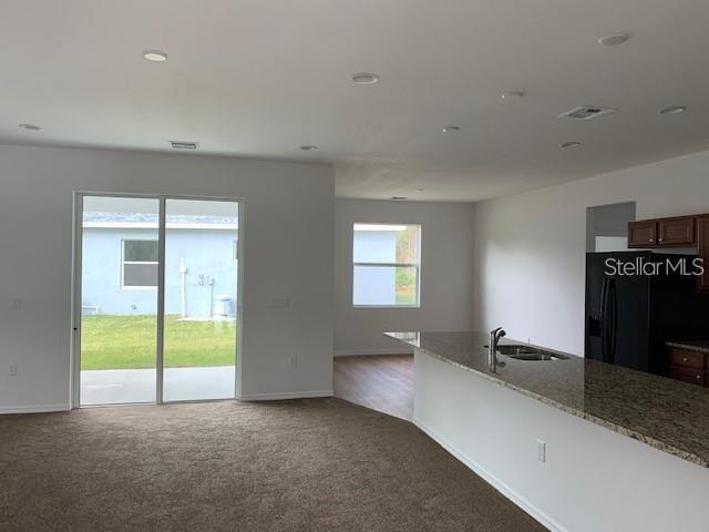 An open-concept living area features a kitchen island, granite countertops, and sliding glass patio doors — 1455 HARBELL STREET, NORTH PORT, FL