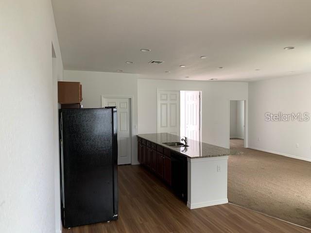 A kitchen with a black refrigerator, dark cabinets, and a granite-topped island — 1455 HARBELL STREET, NORTH PORT, FL
