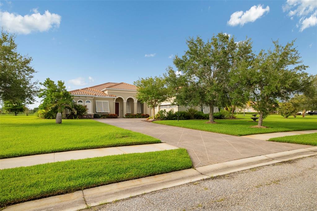 A single-story house with a tiled roof and a paved driveway sits on a lawn — 8420 WEBBER ROAD, SARASOTA, FL