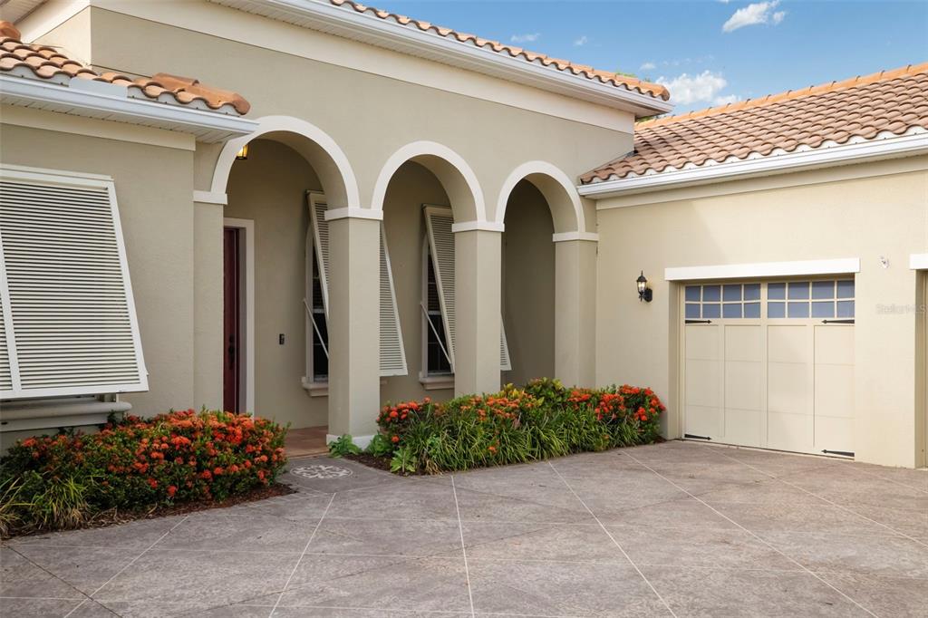 The exterior of a house features a tiled roof, arched entryway, and a garage door — 8420 WEBBER ROAD, SARASOTA, FL