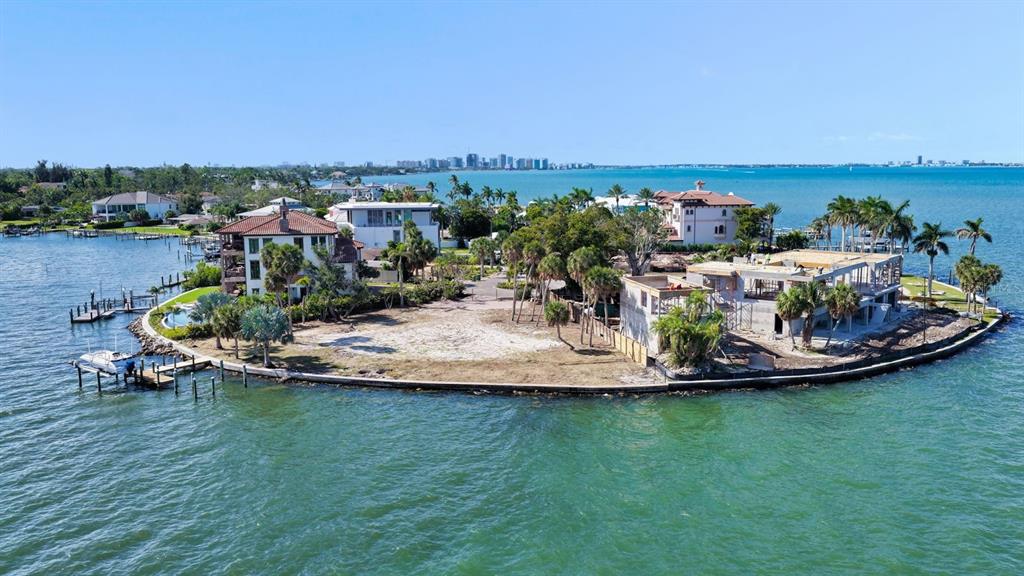 An aerial view shows a waterfront property with a finished house and a construction site — 305 S SHORE DRIVE S, SARASOTA, FL