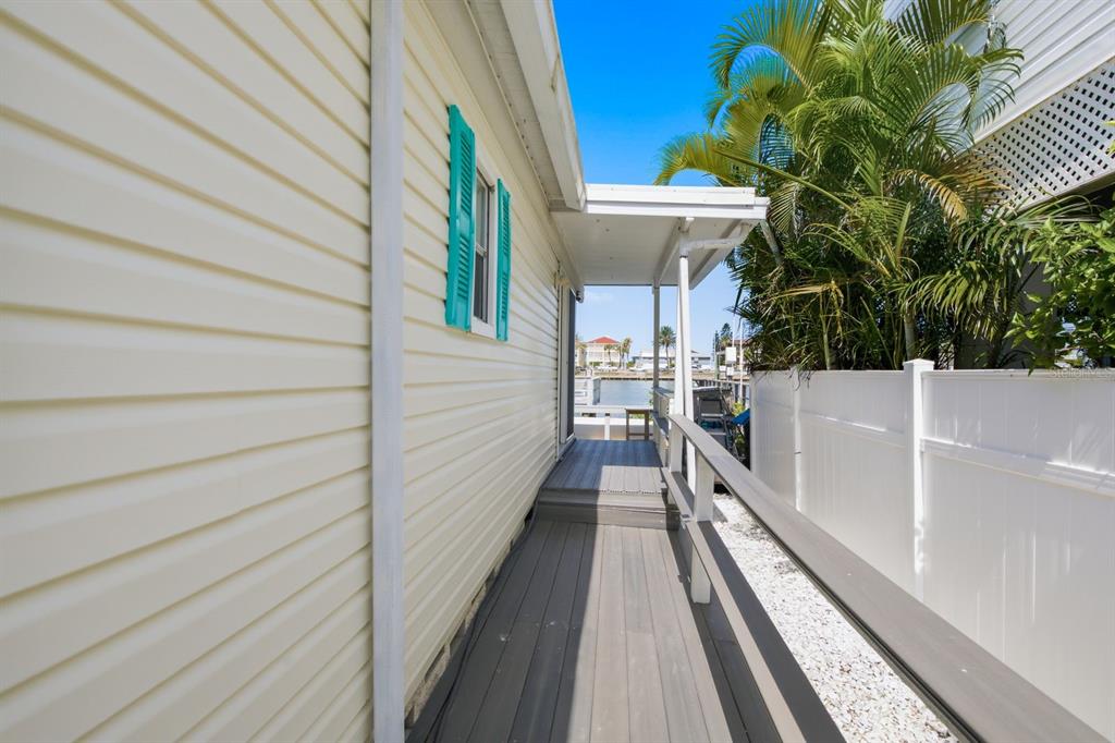 A narrow wooden deck leads toward a waterfront view between a house and a fence — 15010 113TH AVENUE UNIT 12, LARGO, FL